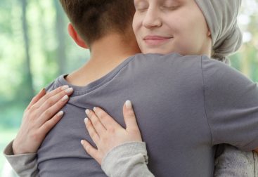 Female cancer patient getting hug from friend